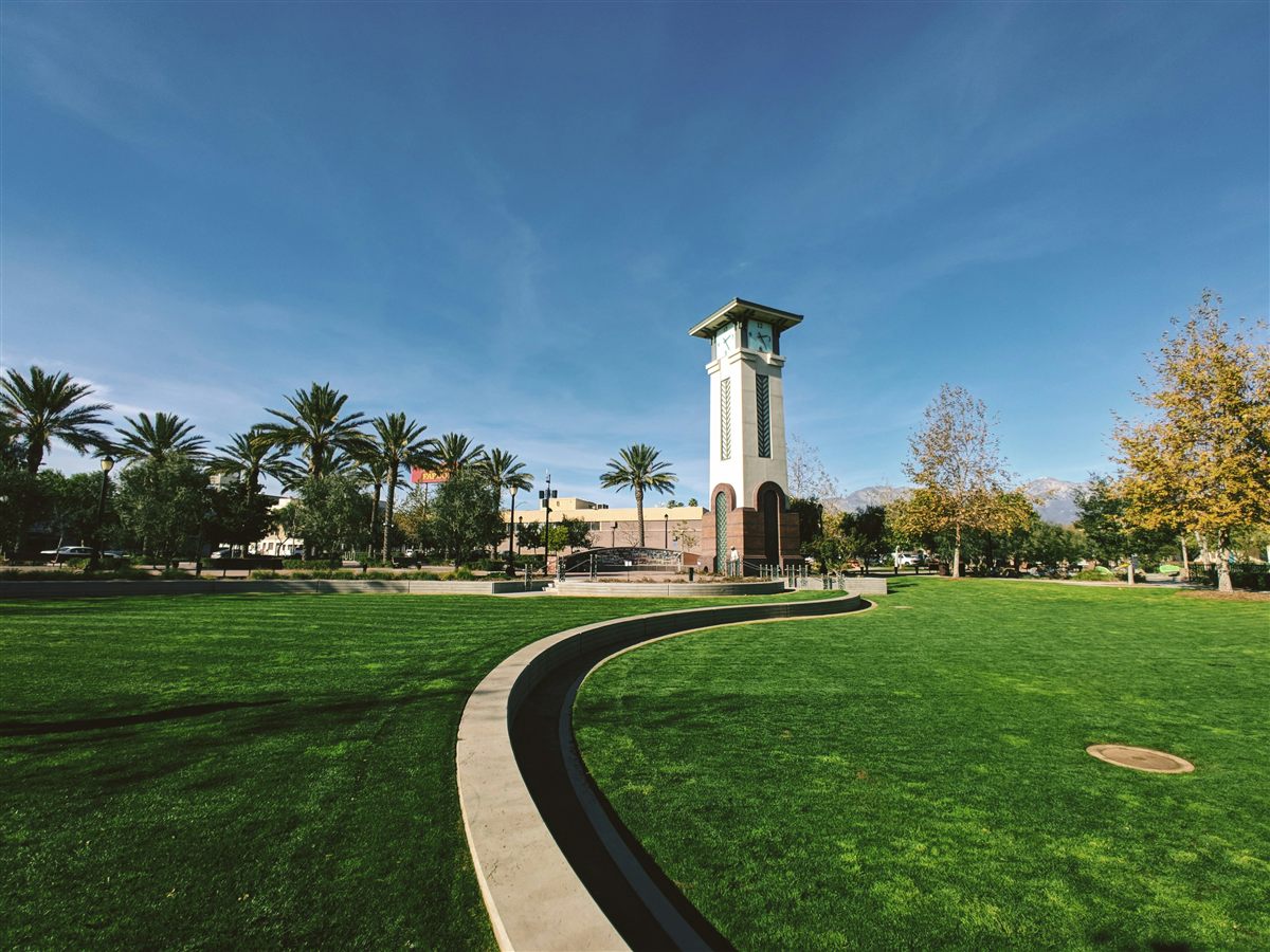 Milliken Park clock tower in Ontario, California, with palm trees and blue sky