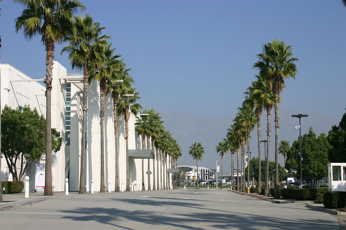 Ontario Convention Center lined with tall palm trees and the San Gabriel Mountains in the background
